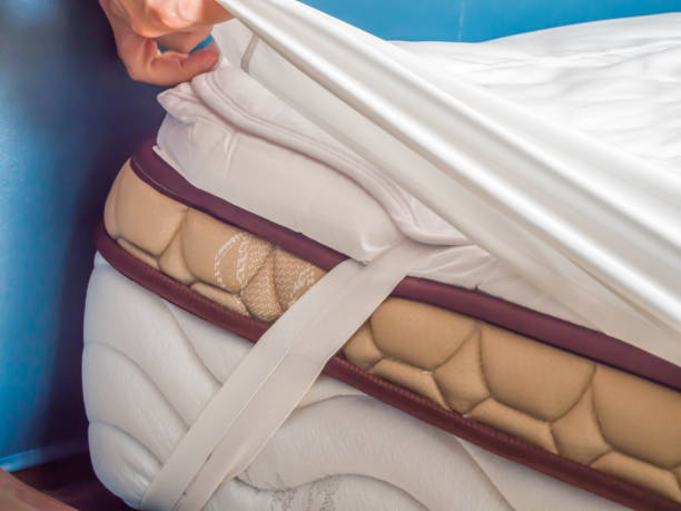 Woman is putting the bedding cover or mattress pad on the bed or putting off for cleaning process.